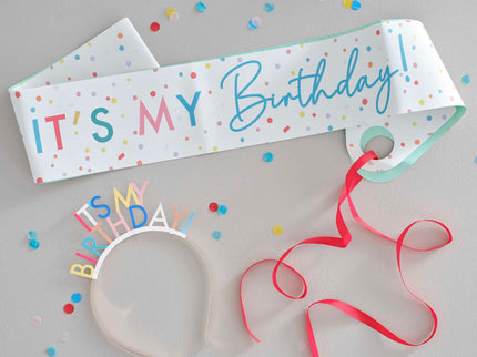 Gimtadienio diena turi būti linksma ir džiugi! Šią spalvingą šventinę juostą ir galvos lankelį  užrašu "It's My Birthday" būtina turėti per kiekvieną gimtadienio šventę. Padovanokite gimtadienio kaltininkui arba nusipirkite patys! Šiuos gimtadienio aksesuarus derinkite su spalvingomis dekoracijomis iš mūsų vakarėlių ar gimtadieninių kolekcijų. Pakuotėje yra 1x gimtadienio galvos lankelis ir 1 x reguliuojama 155 cm ilgio juosta.
